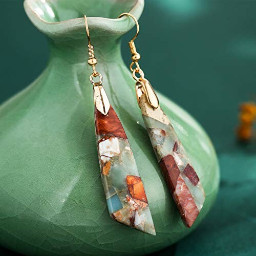 Bohemian style drop earrings with mosaic design on a green vase.