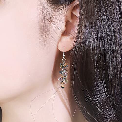 Close-up of a woman's ear wearing dangling beaded earrings.